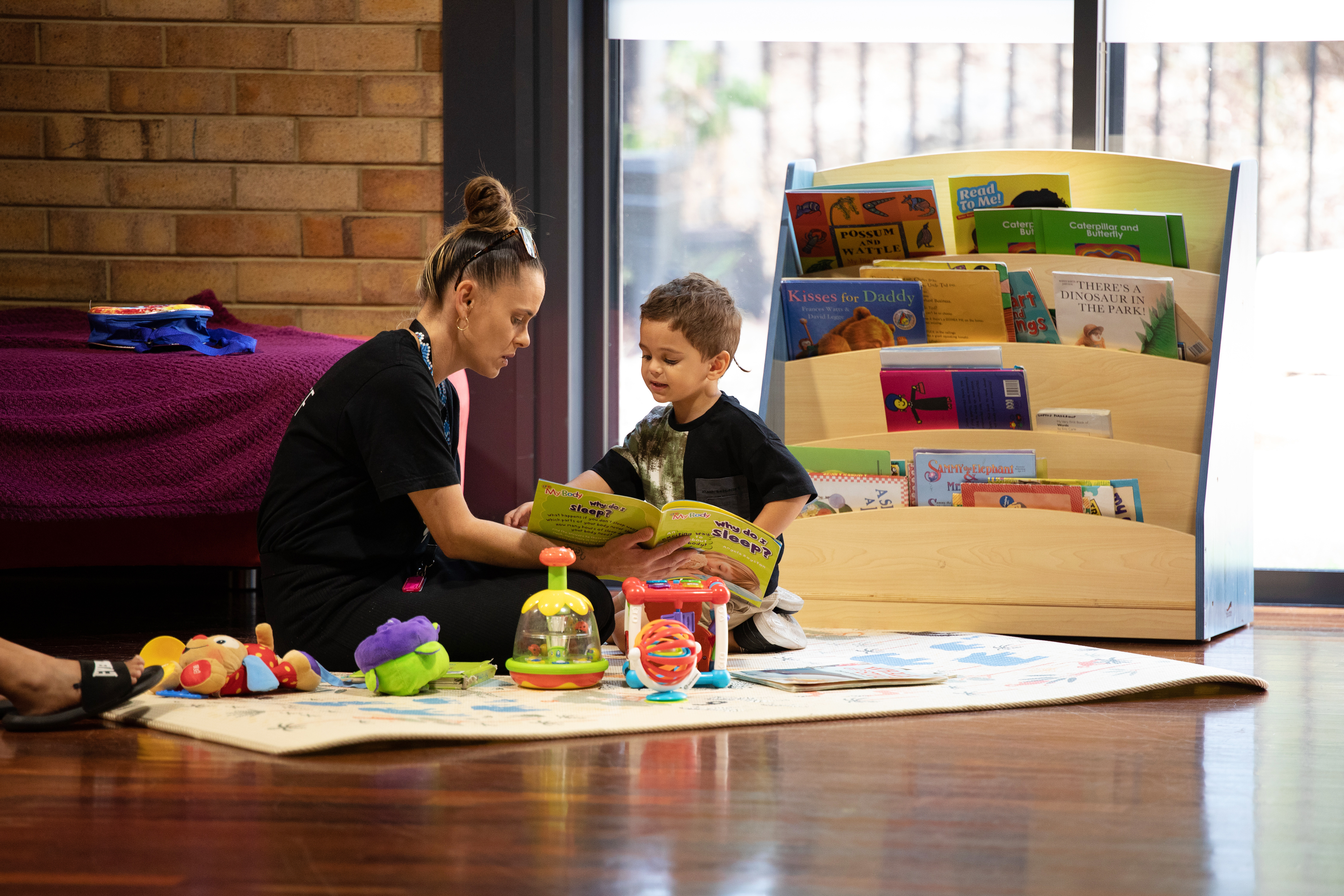 Carer and child reading together on a play mat