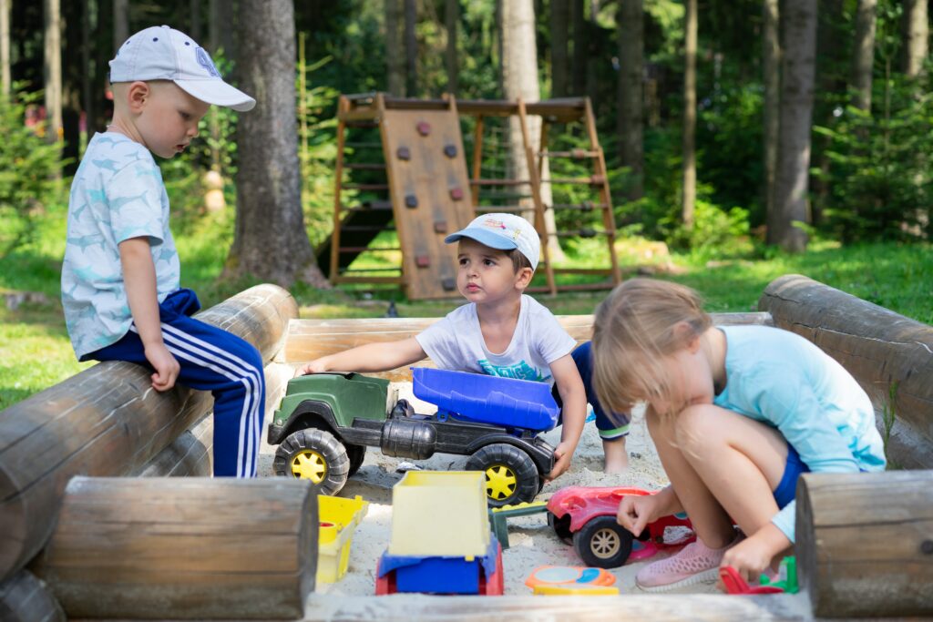 three young kids playing outside in a sandbox